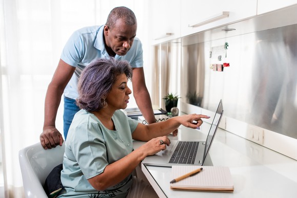 Two people with serious expressions looking at a laptop.
