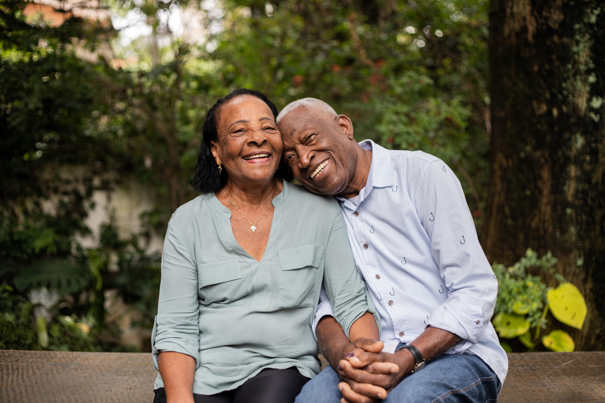 Two smiling people sitting outdoors.