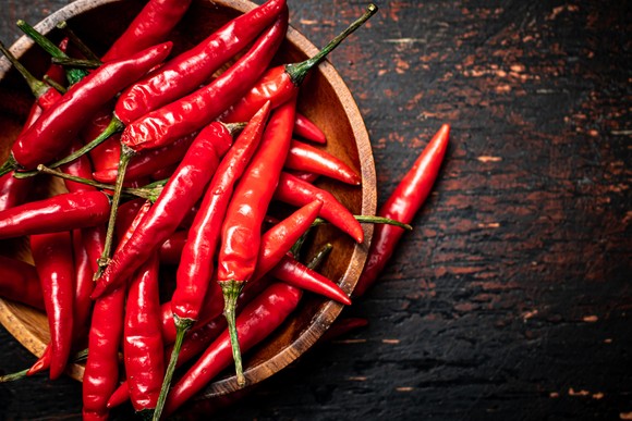 Chili peppers in a wooden bowl on table. 