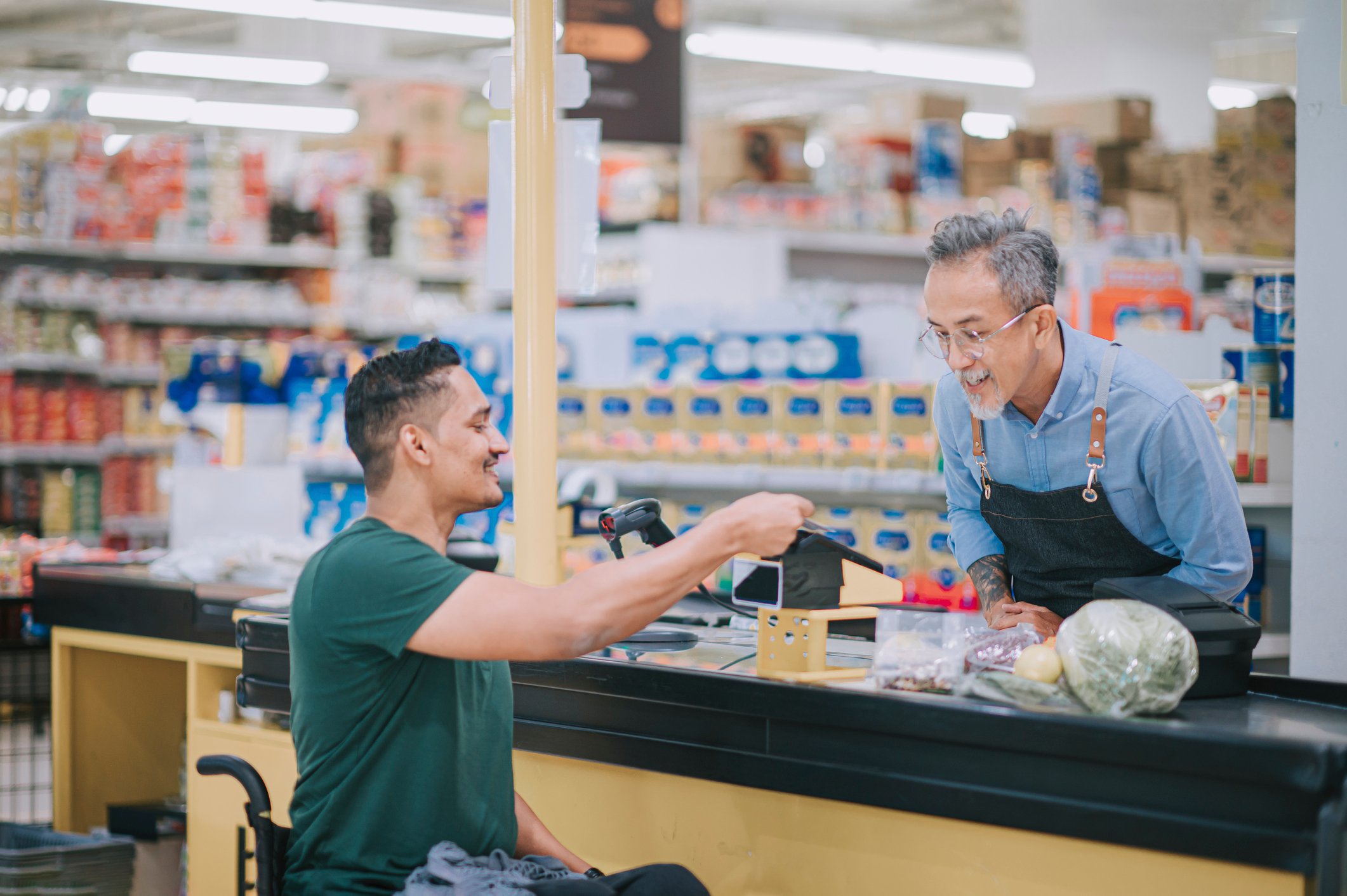 A person makes a payment at a grocery store checkout.
