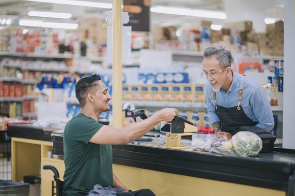 A person makes a payment at a grocery store checkout.