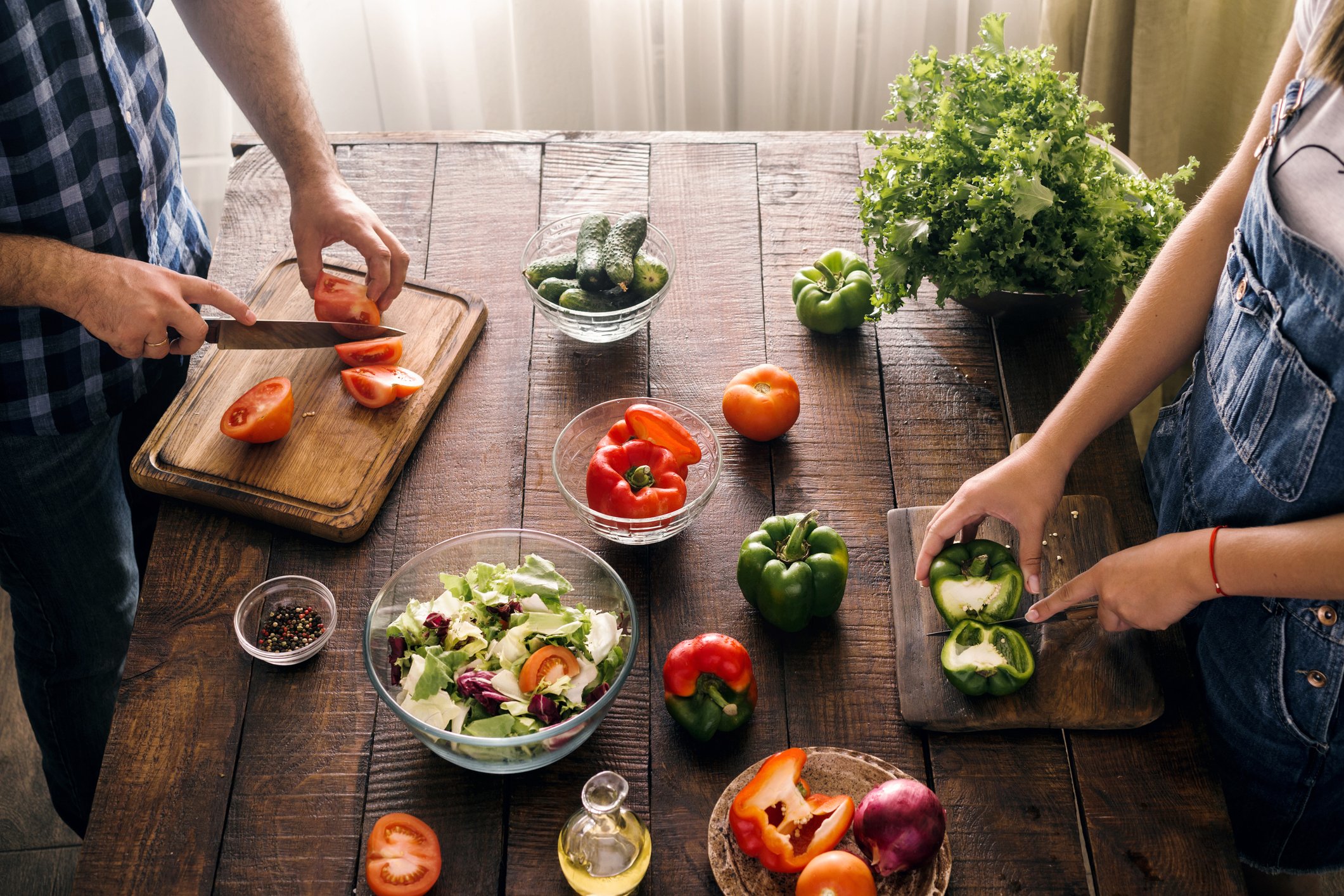 Two people prep food on a rustic table
