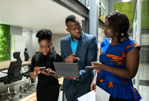 Three business colleagues with laptops and smartphones.