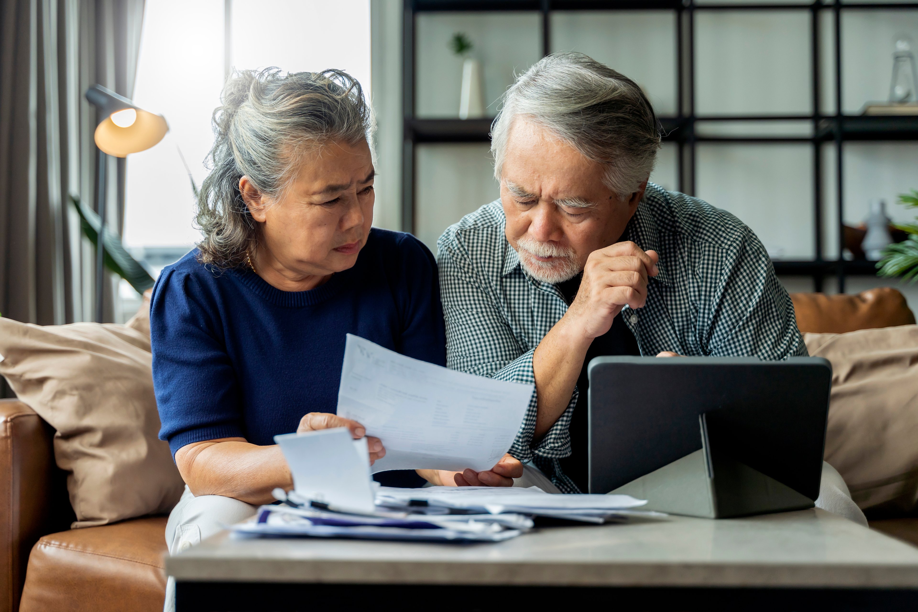 Two people sit on a couch and review paperwork.