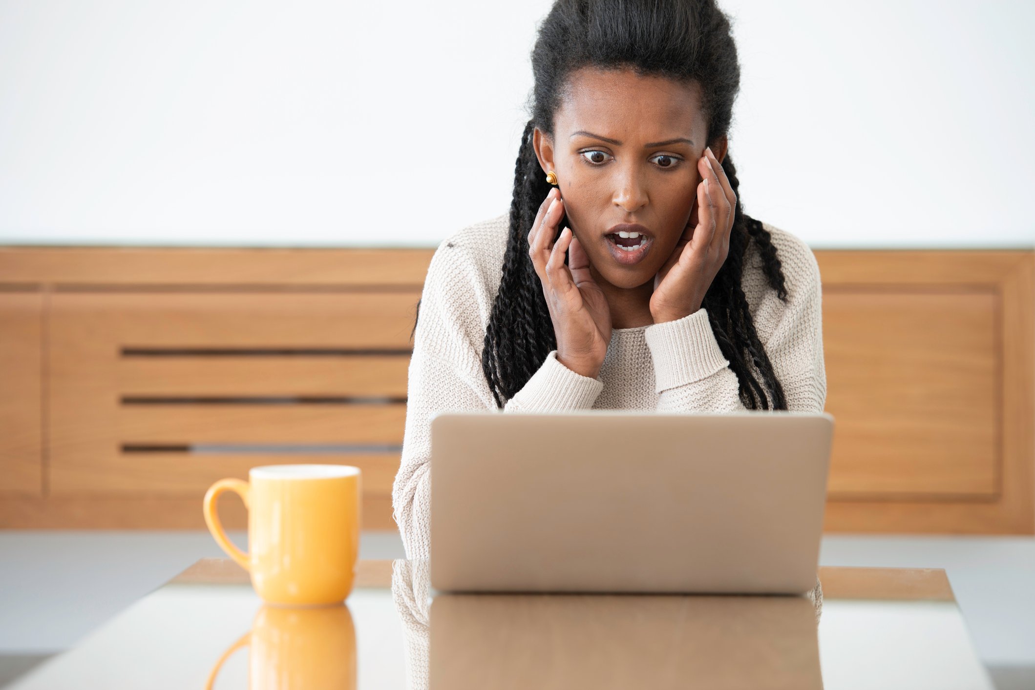 Person sitting in front of laptop looks shocked at the information on the screen.