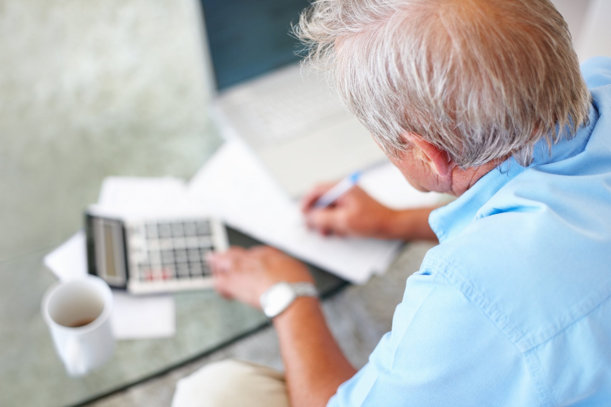 Older man with calculator at desk. 