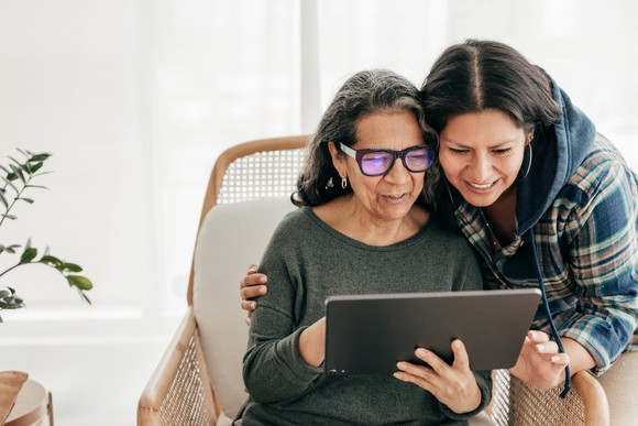 Two people looking at a tablet and smiling.
