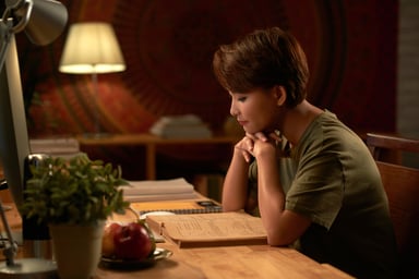 Student reading book in dimly lit study