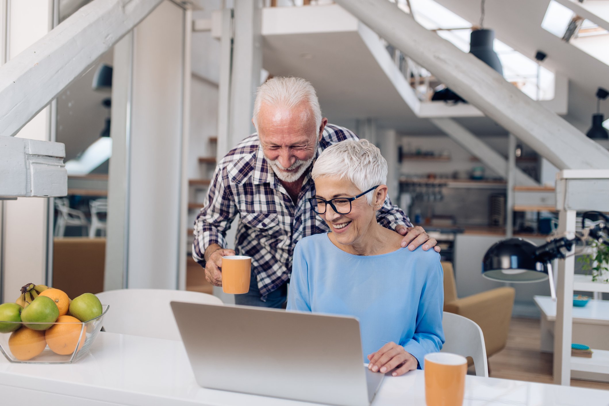 Two people look at a laptop screen while drinking coffee together