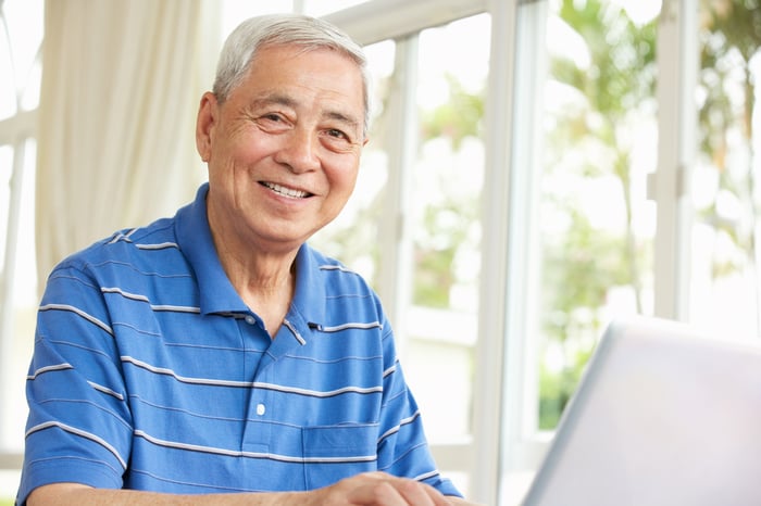 A smiling person at a laptop.