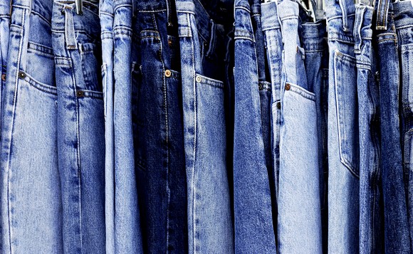 Many pairs of blue jeans hanging vertically.