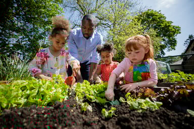 Adult and children work in a garden.