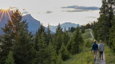 Couple walks down trail at sunrise
