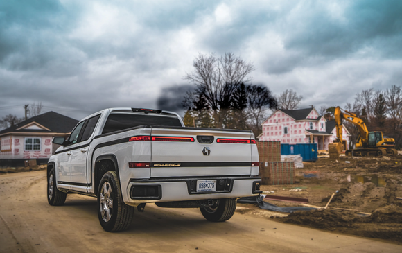 White Endurance electric pickup truck driving on home construction site.