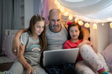 Three people watching a laptop.