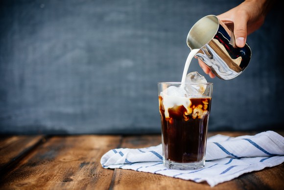 Hand pouring cold coffee drink.