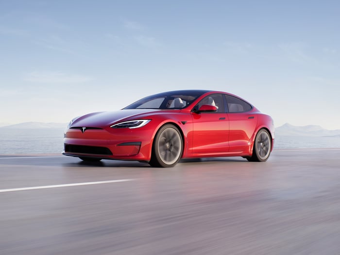 Red Tesla Model S against a scenic background.