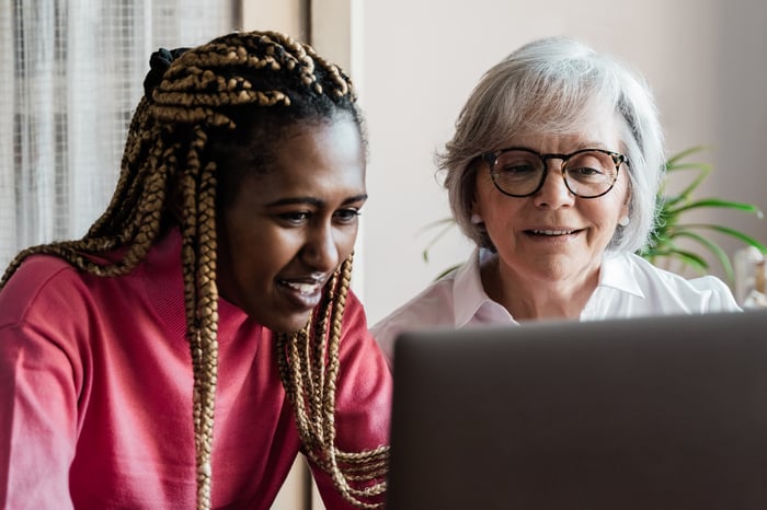 Two people sitting down looking at a laptop.