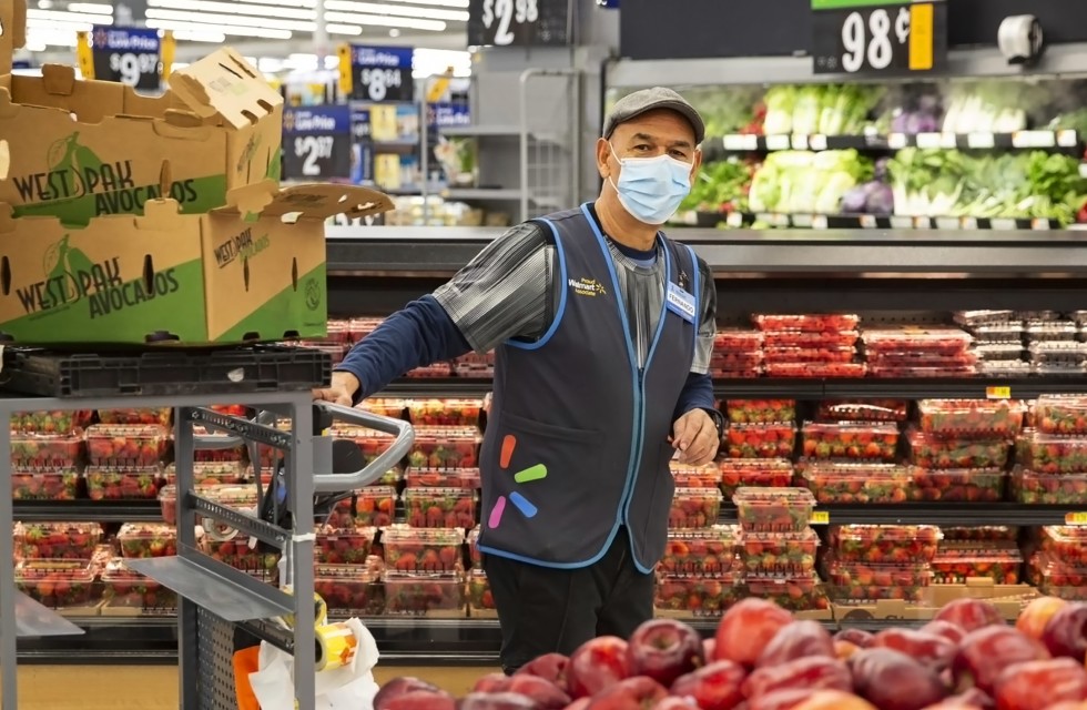 Produce worker at Walmart strolls by amicably. 
