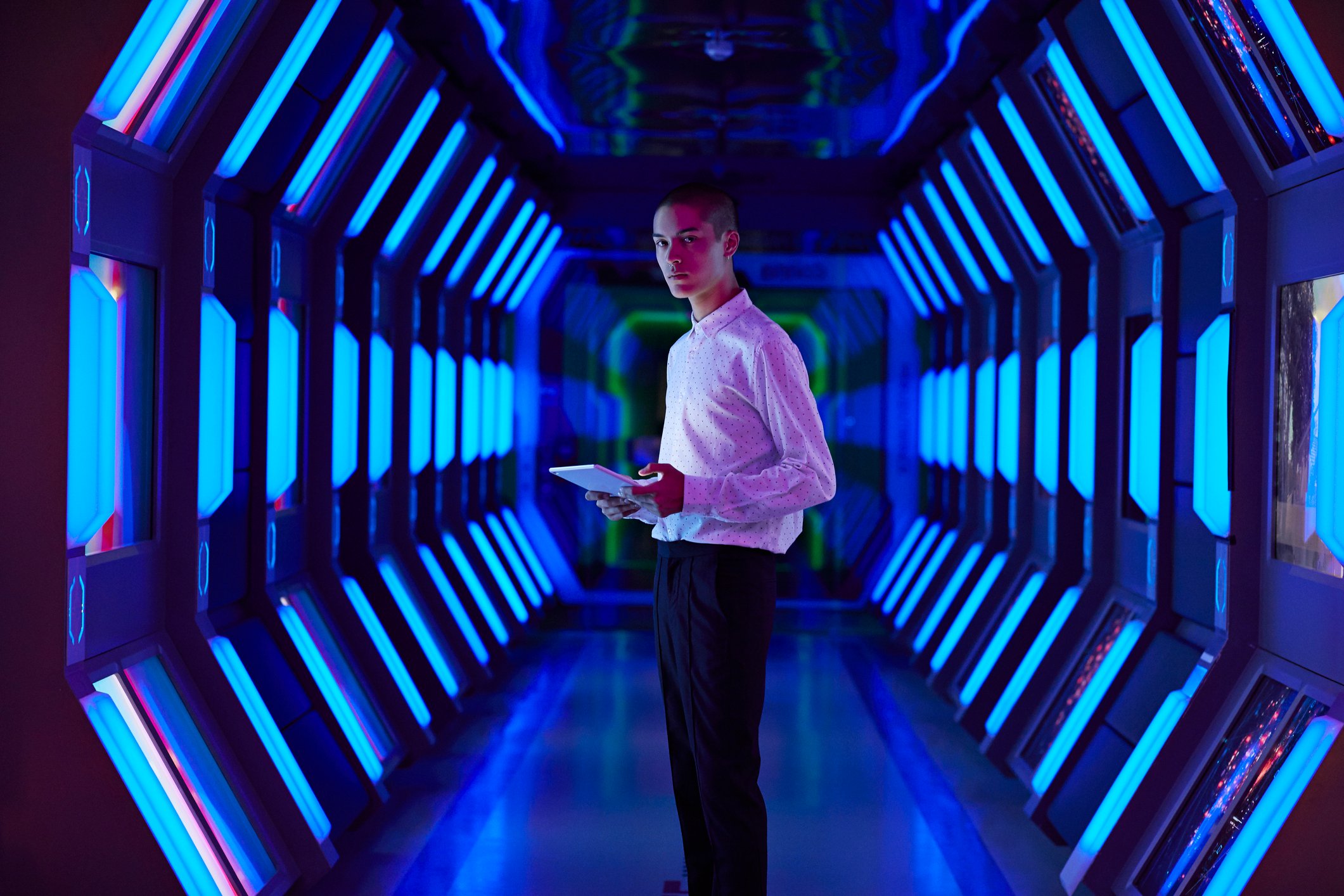 Person with laptop in front of glowing blue screens.