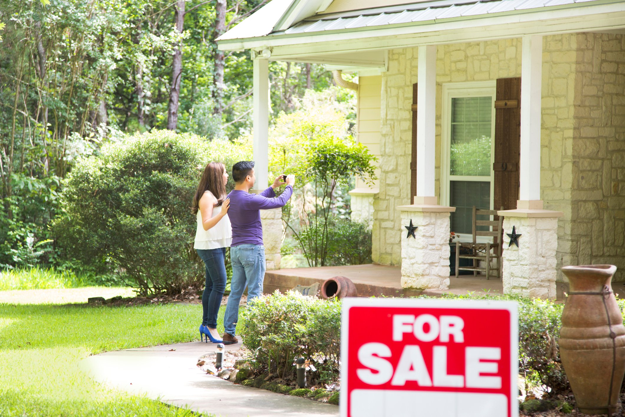 Couple in front of a house for sale. 