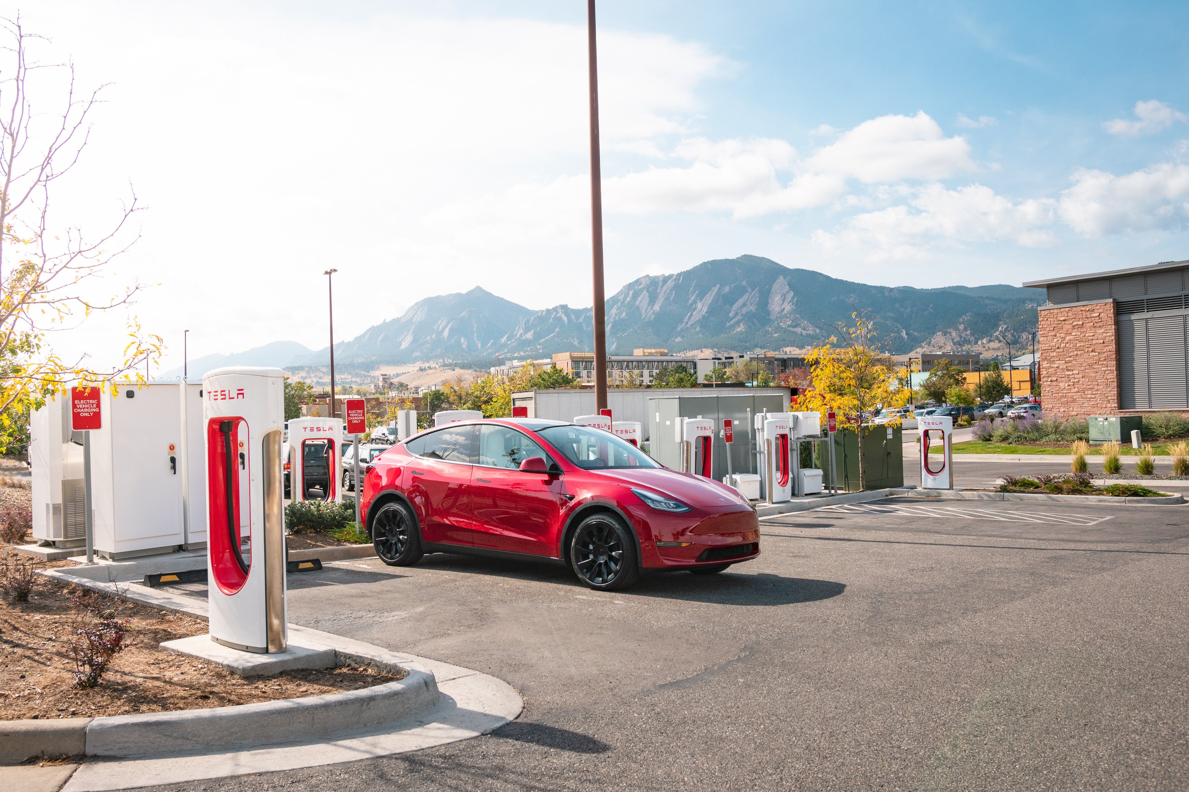 Red Tesla charging at Supercharger site. 