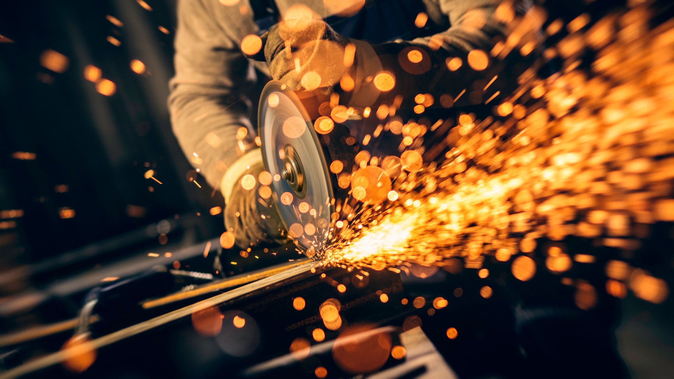 Sparks fly as a person works on an industrial grinder. 