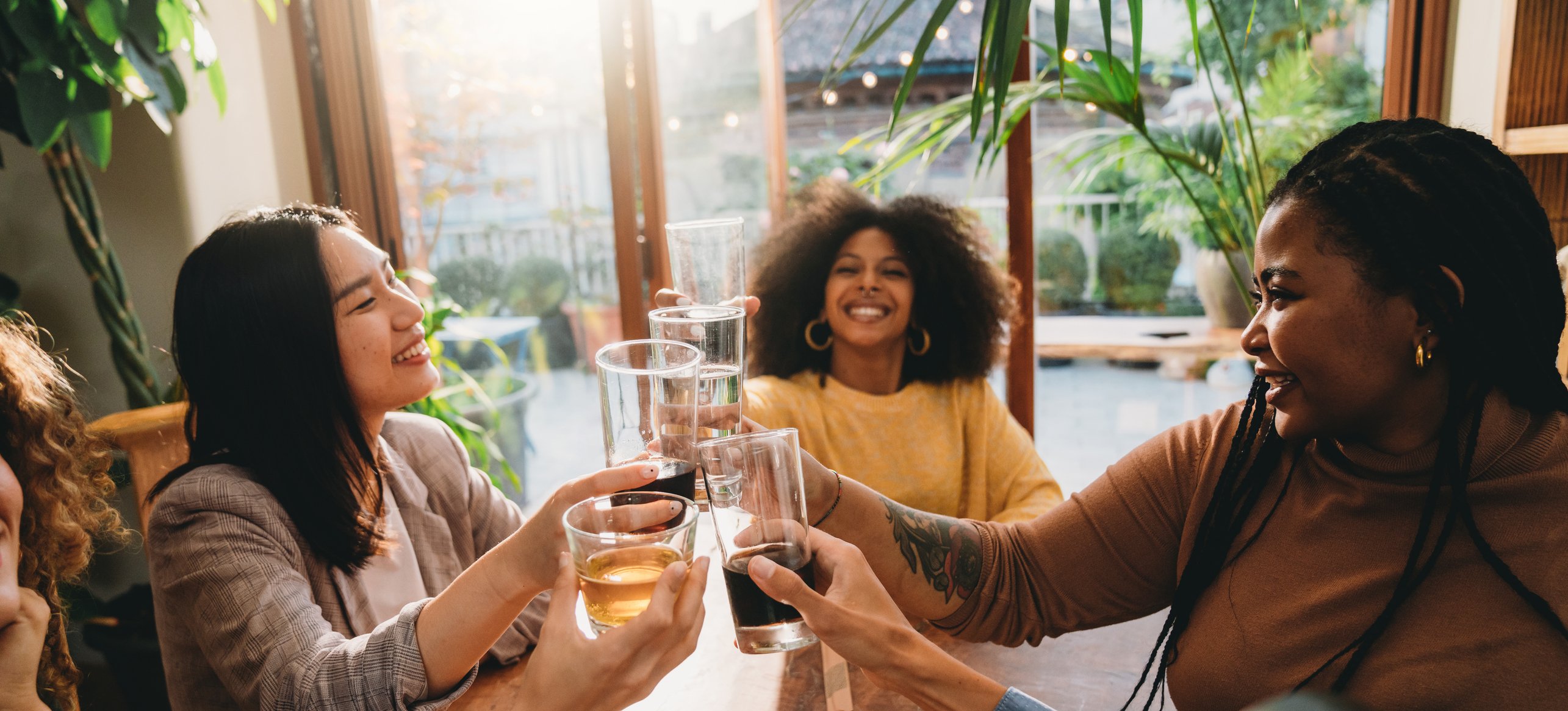 A group of friends raise glasses of soda at a restaurant. 