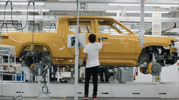 A yellow Rivian R1T electric pickup truck on production line. 