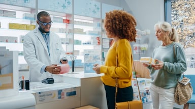 A pharmacist serves customers at a pharmacy