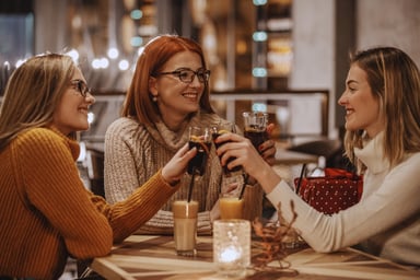 Three people toast their glasses filled with cola