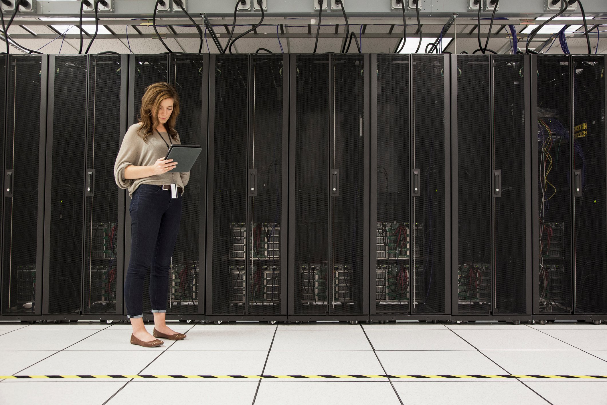 A person standing next to computer servers.