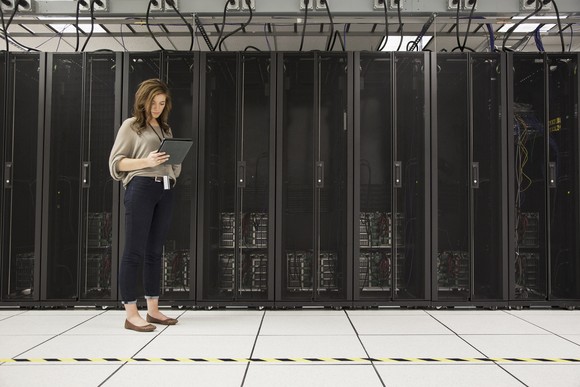 A person standing next to computer servers.