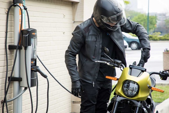 Rider charging an electric motorcycle.