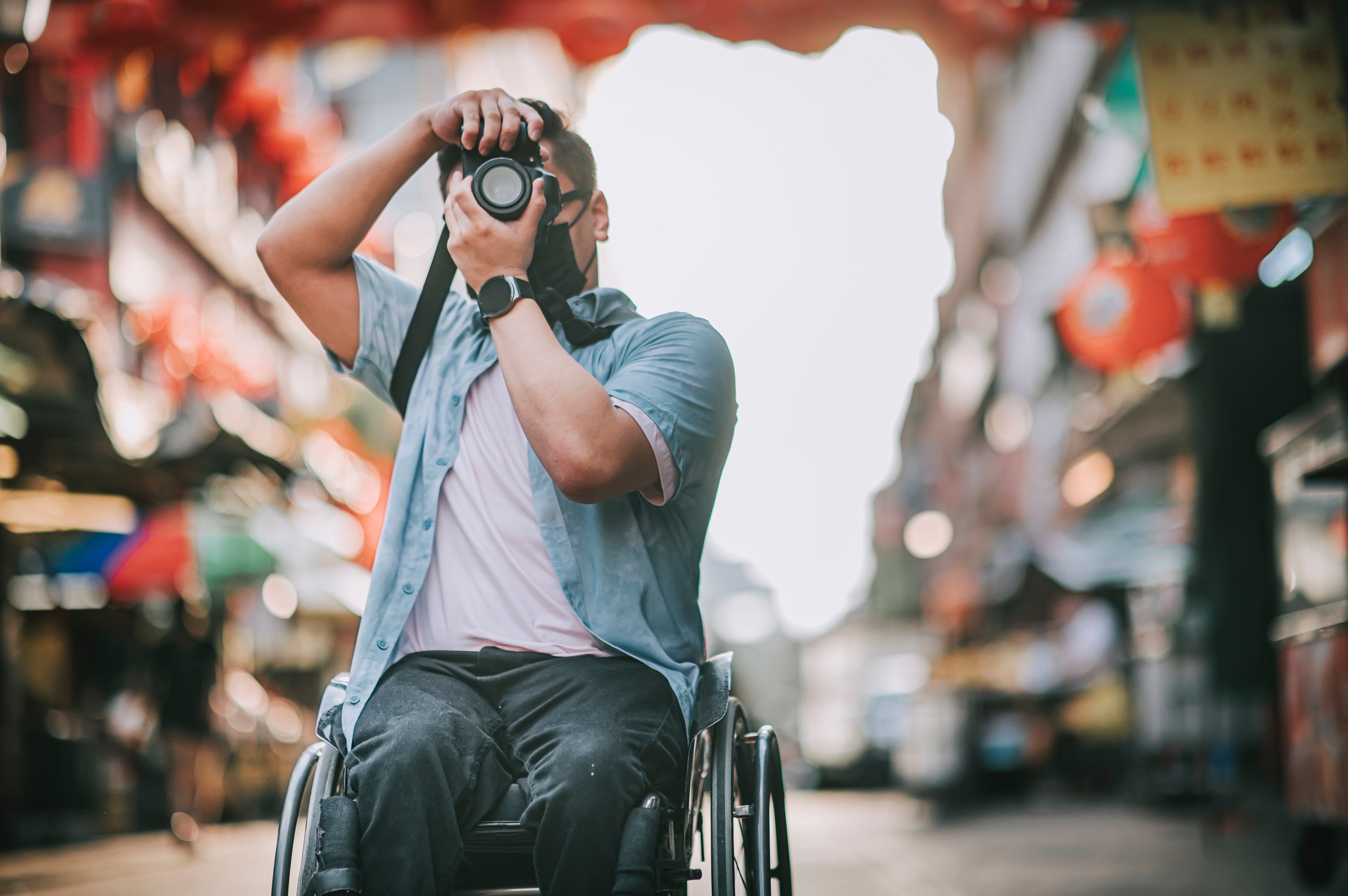 Man in wheelchair taking photograph.