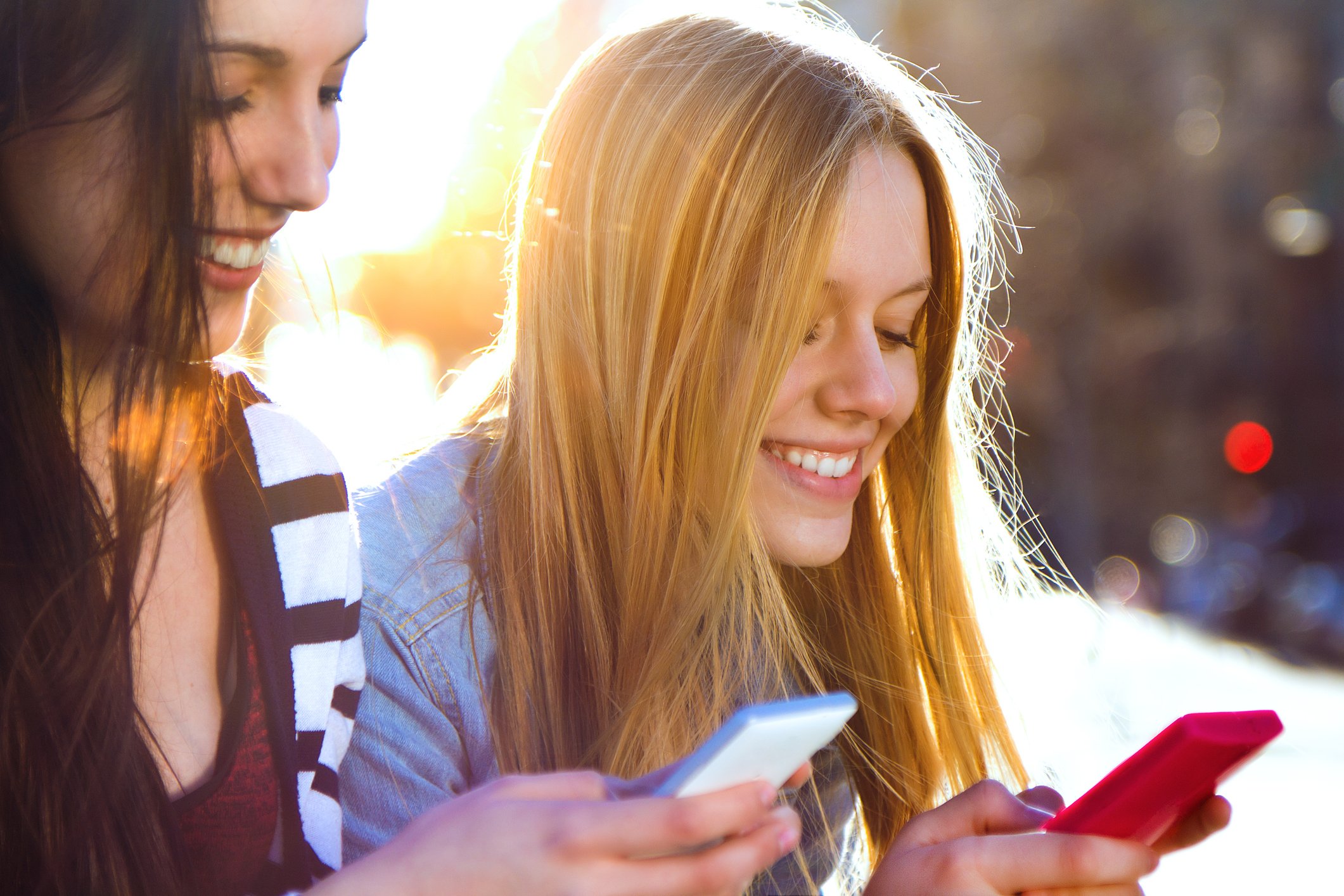 Two smiling people texting on their smartphones. 