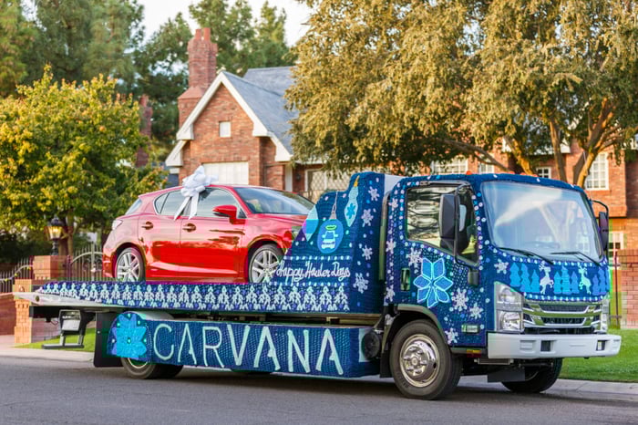 Carvana flatbed truck delivering a vehicle.