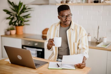 Man working from home reviewing a sheet of paper.