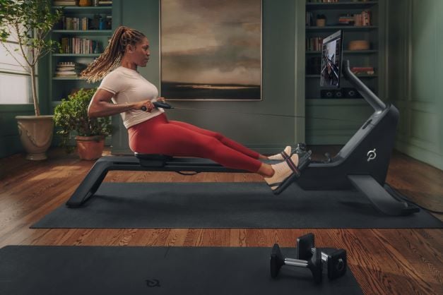 A black woman works out in her home gym on the new Peloton Row.