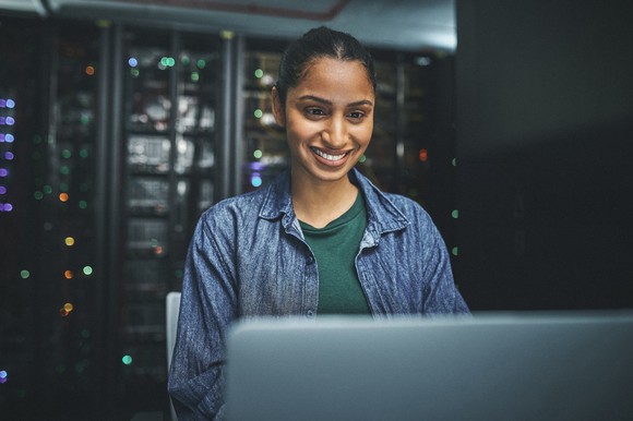 An IT professional works on a computer in a server room.