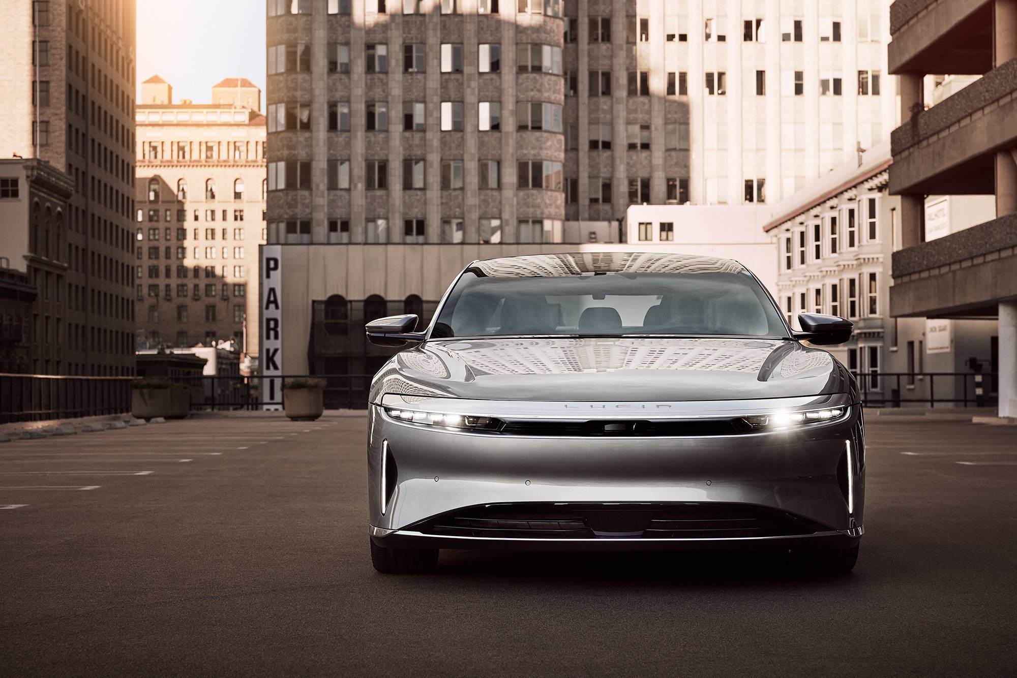 A silver Lucid Air sedan in big city setting.