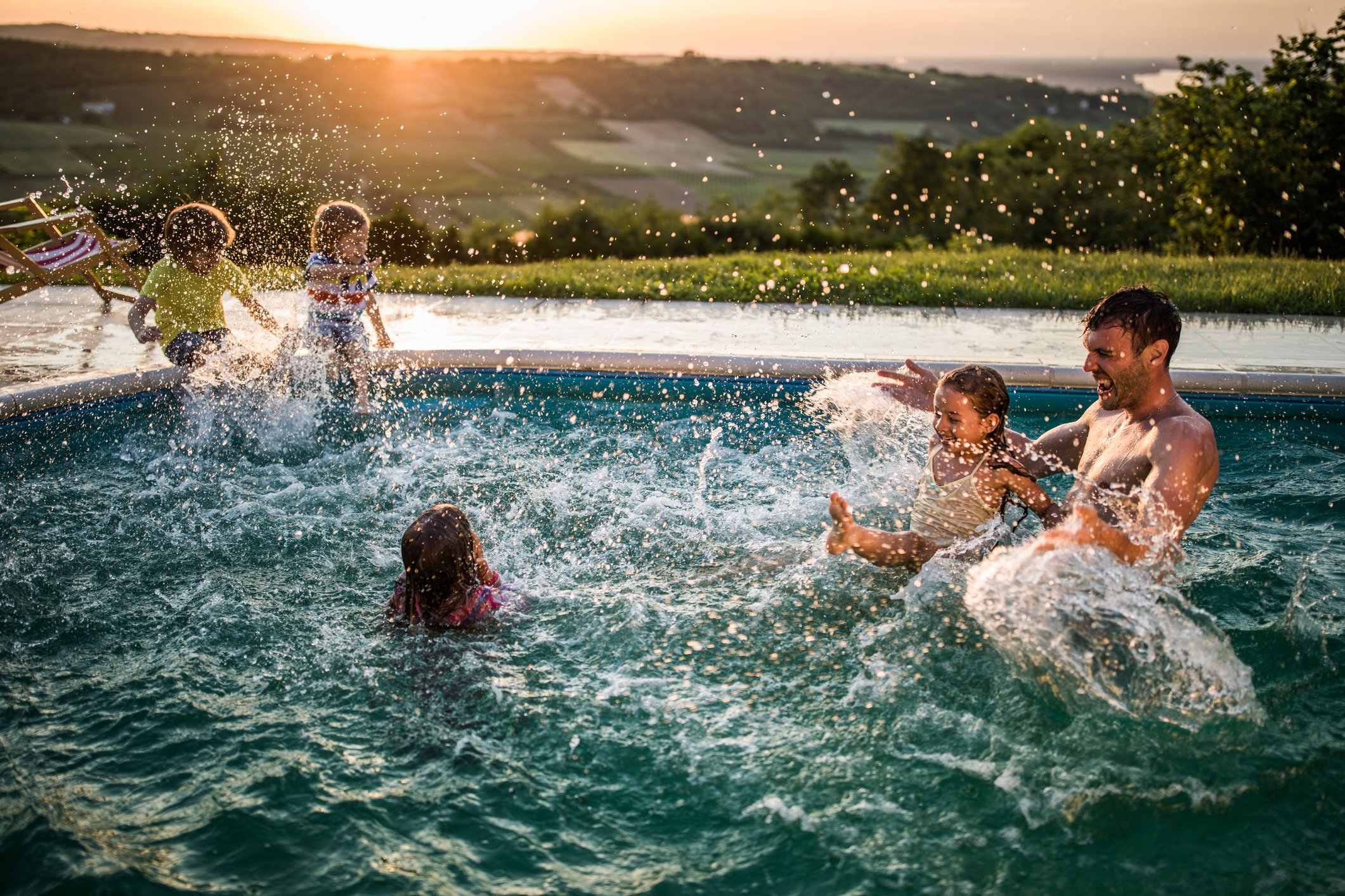 Several people in a swimming pool, with a landscape background.