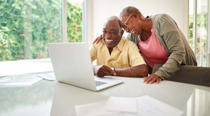 Smiling people looking at laptop together.