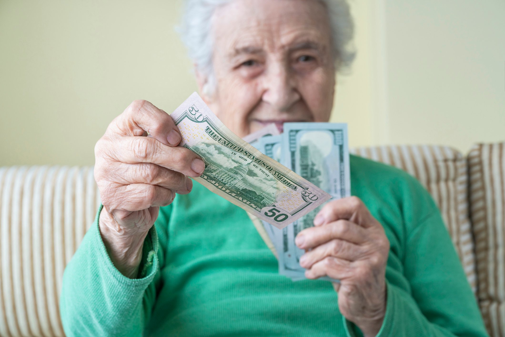 Person sitting on couch holding cash in hands.
