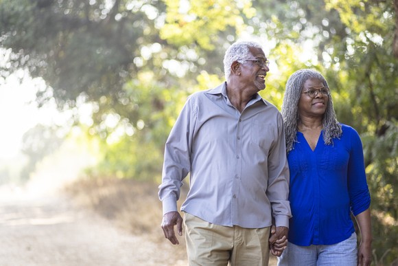Two people holding hands walking down road.