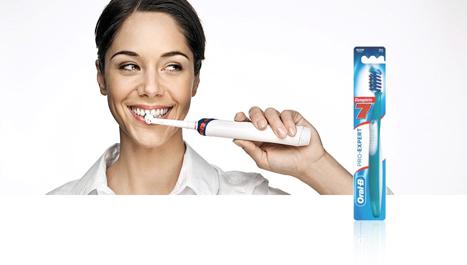 Smiling women brushing her teeth with an Oral-B toothbrush.