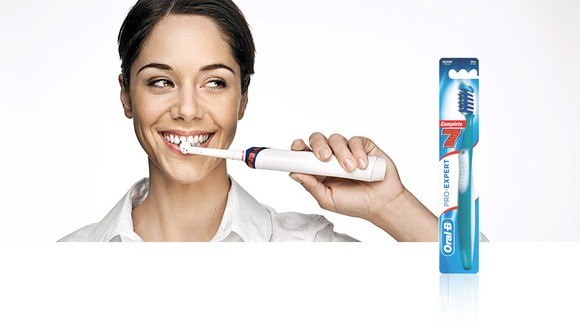 Smiling women brushing her teeth with an Oral-B toothbrush.
