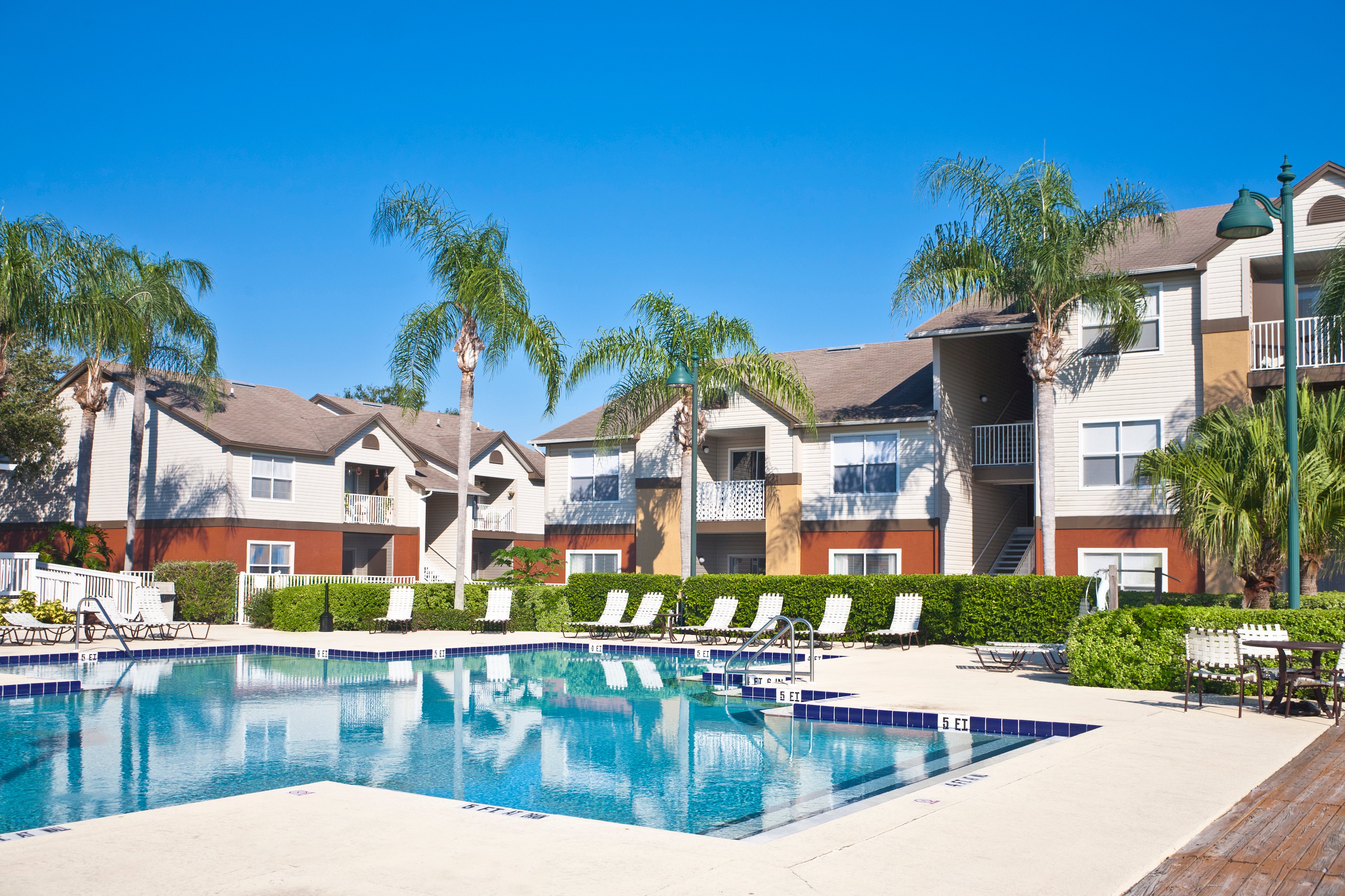 An apartment complex by a pool and palm trees.
