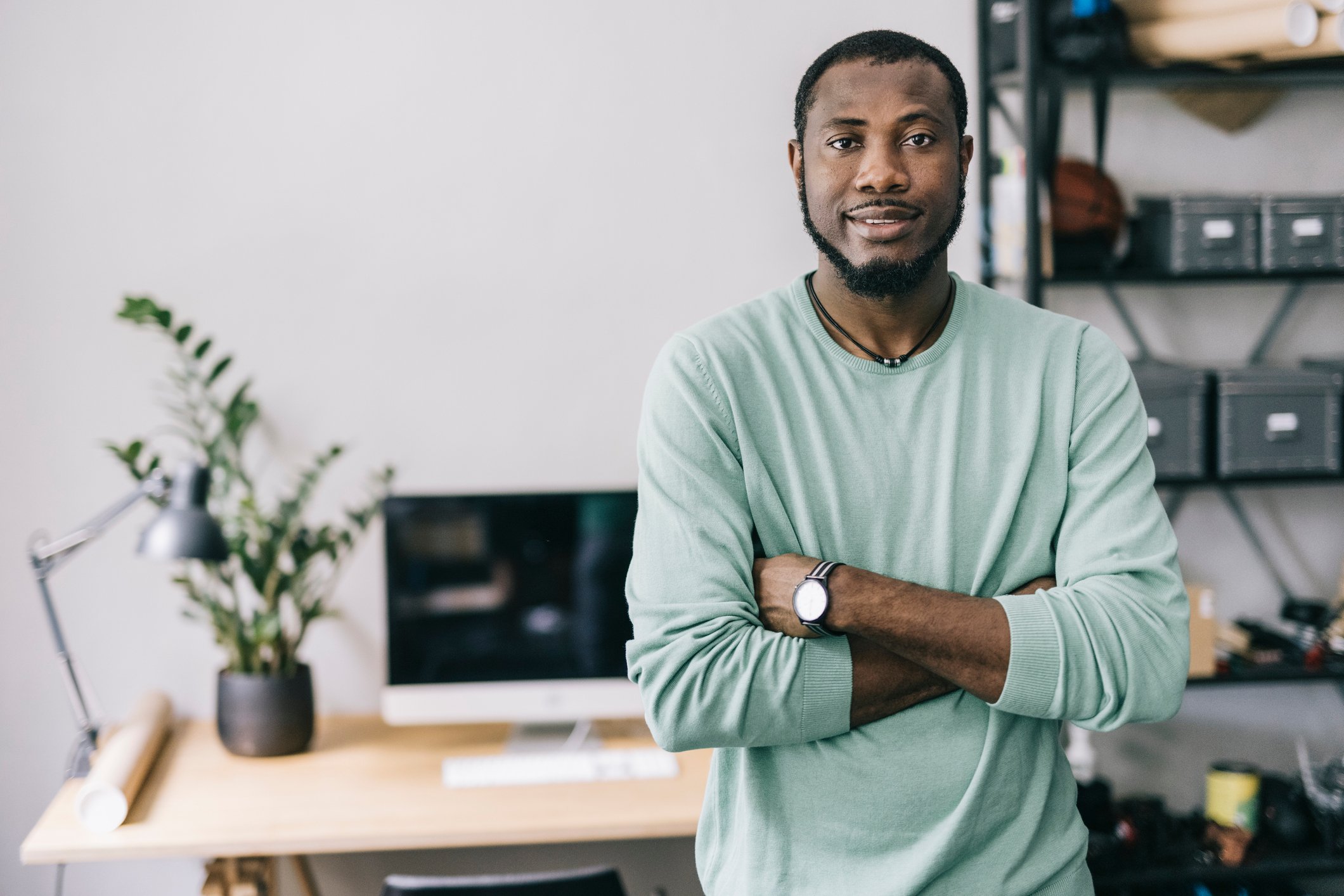 A person standing in their home office with their arms crossed.