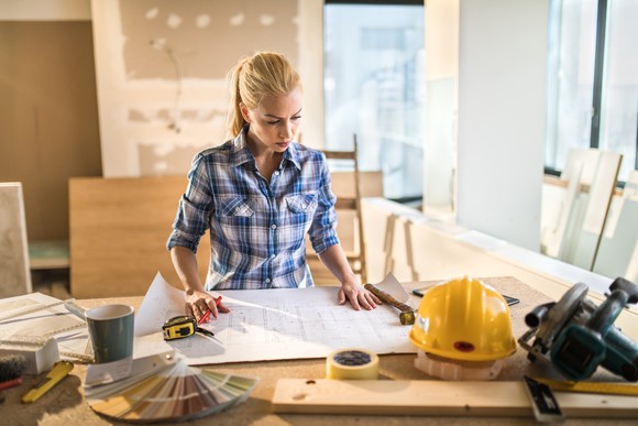 Person at work table on construction site looking at plan documents.
